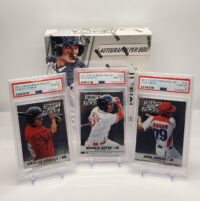 Three graded baseball cards featuring players carlos correa, mookie betts, and jose abreu in plastic cases, with a 2013 Panini Prizm Draft Hobby - By The Pack With PSA Bonuses box in the background.